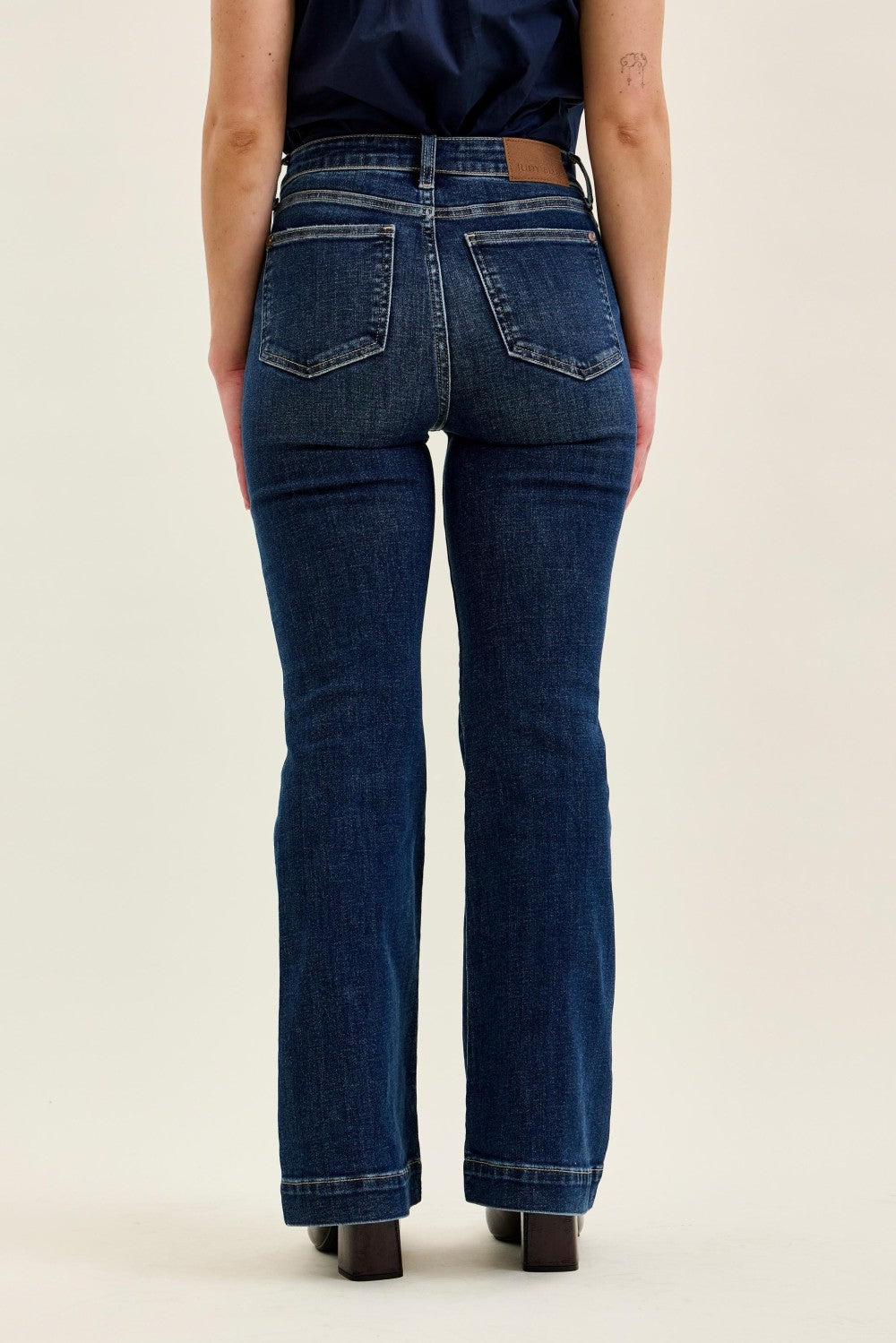 Dark blue high-rise Judy Blue petite flare jeans with classic five-pocket design, belt loops, and a leather patch on the waistband, full length
