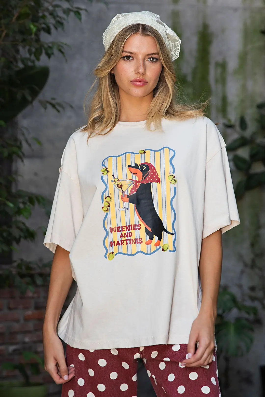 Cream women’s graphic T-shirt featuring a dachshund holding a martini with “Weenies and Martinis” lettering and colorful retro details.