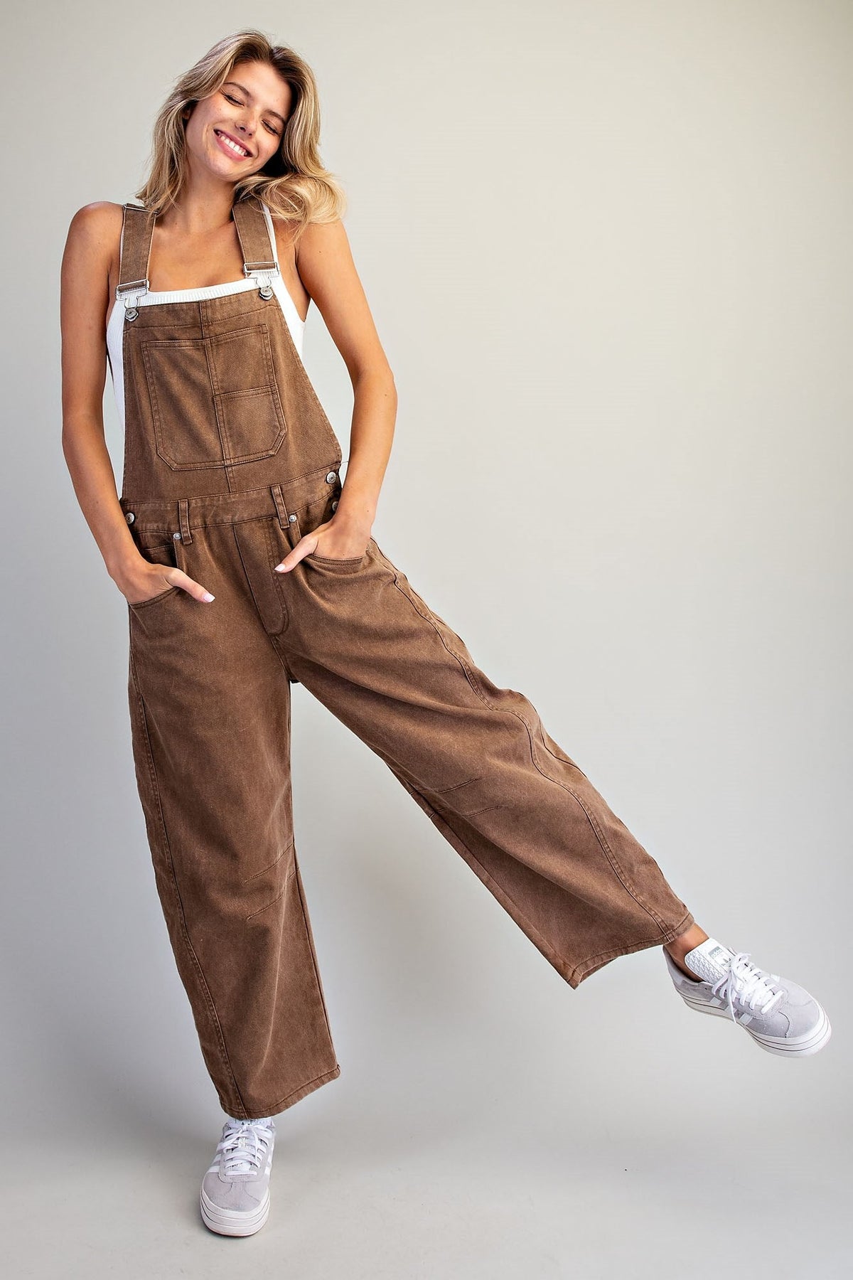 Women smiling with eyes closed wearing brown mineral wash barrel overall with adjustable shoulder straps, front pocket, and relaxed fit