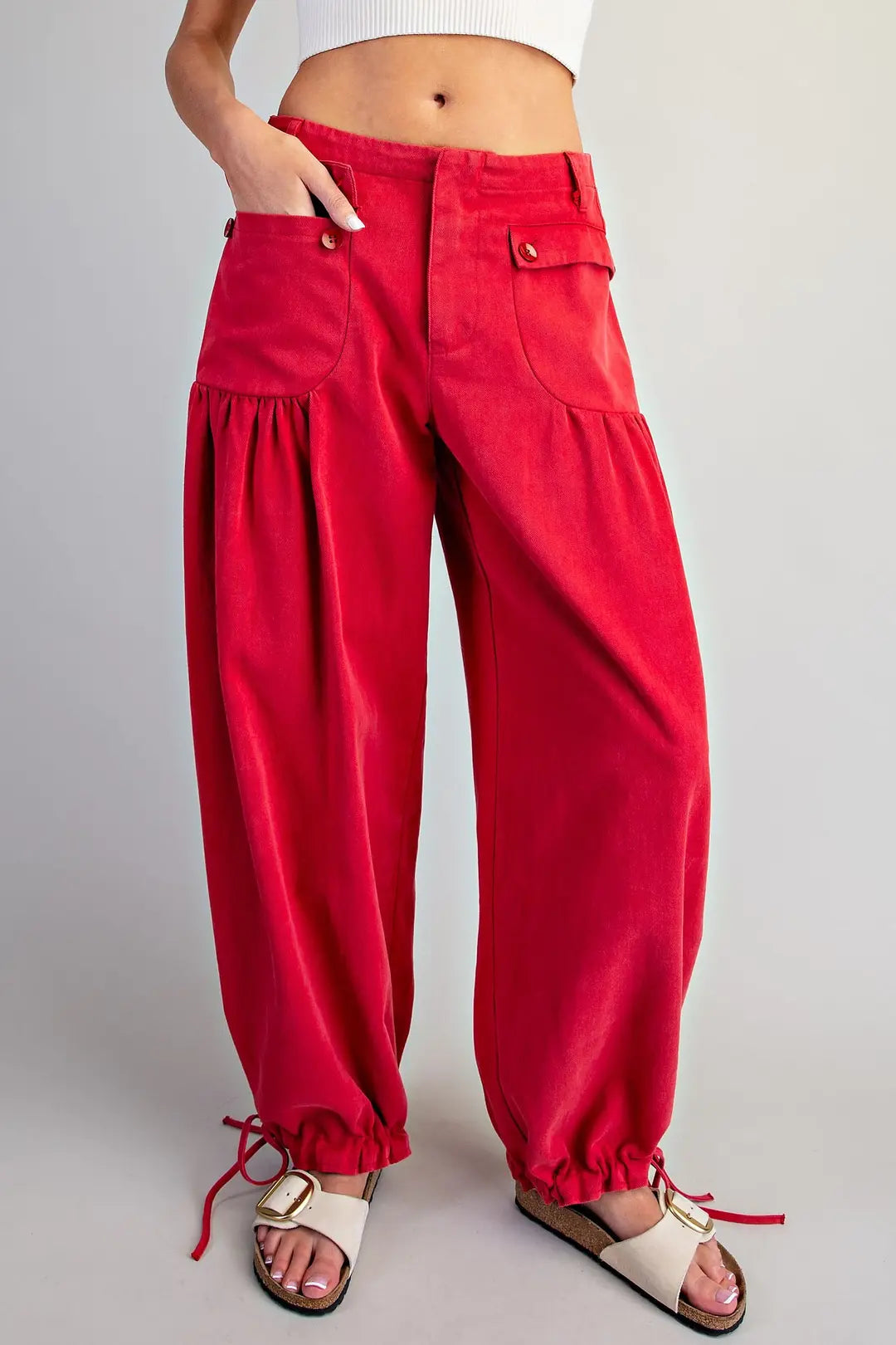 Women's red cotton cargo pants with oversized button front pockets, gathered detailing, relaxed legs and adjustable tie ankle hems.
