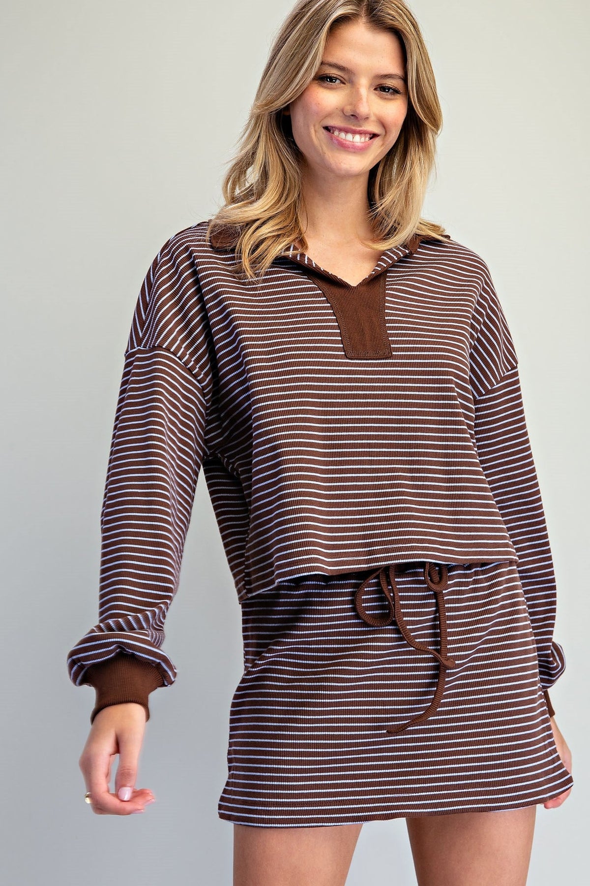 Model wearing a brown and white striped long-sleeve skort set with elastic waistband and built-in shorts, casual lounge style.
