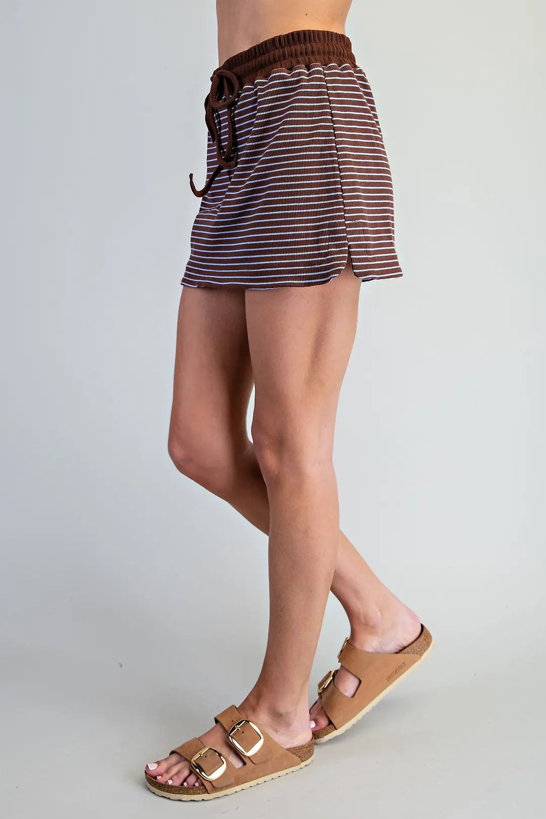 Back view of brown striped skort with elastic waistband and slit, paired with tan sandals, casual summer look