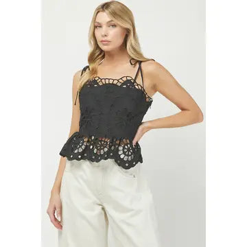 Woman wearing a black lace top and white pants on a white background