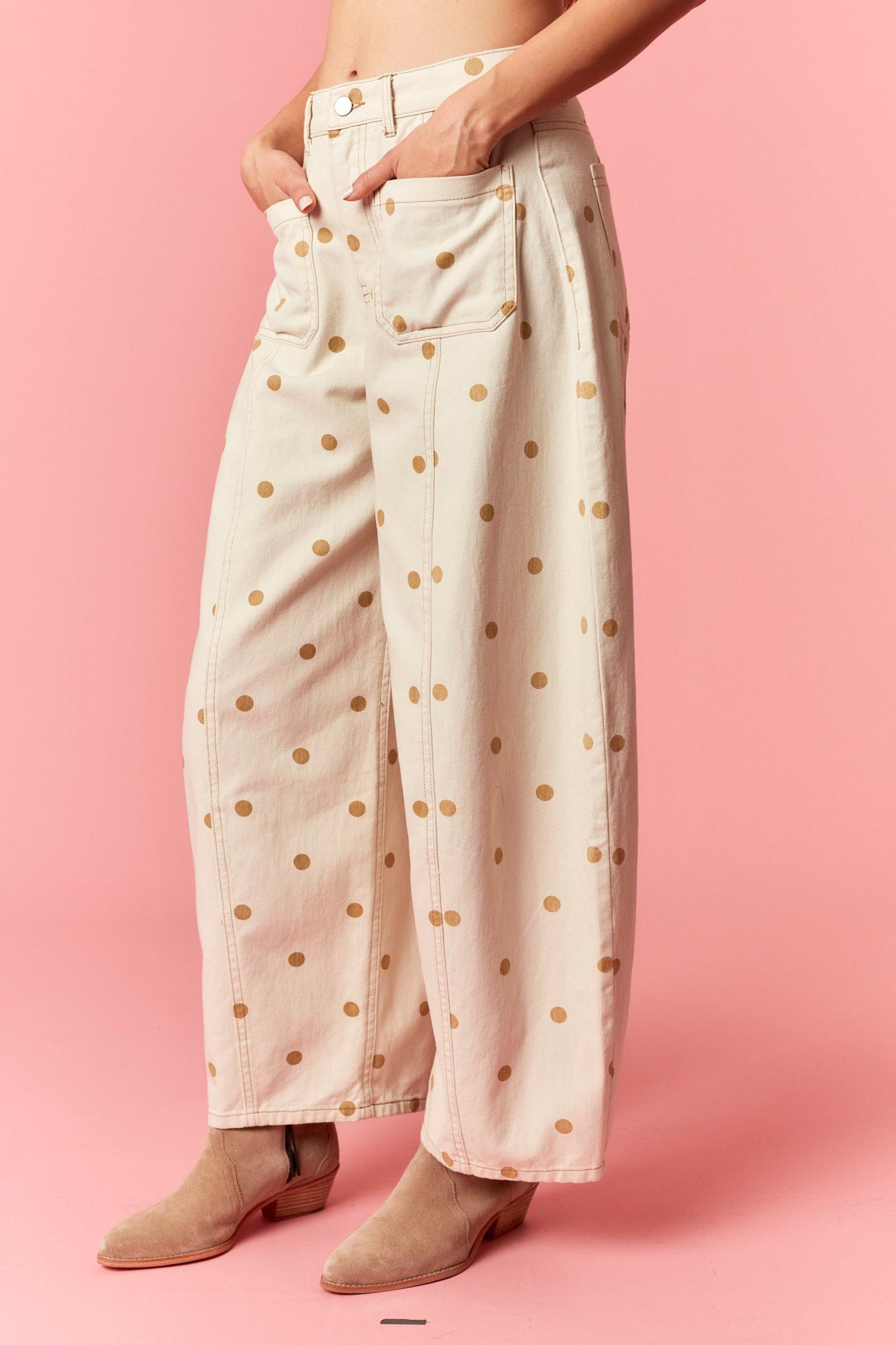 Person wearing light pink pants with gold polka dots on a pink background