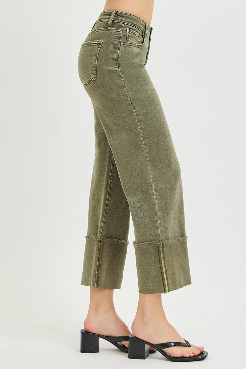 Side view of olive green wide leg jeans with distressed frayed hems, high waist, and relaxed silhouette, paired with heels