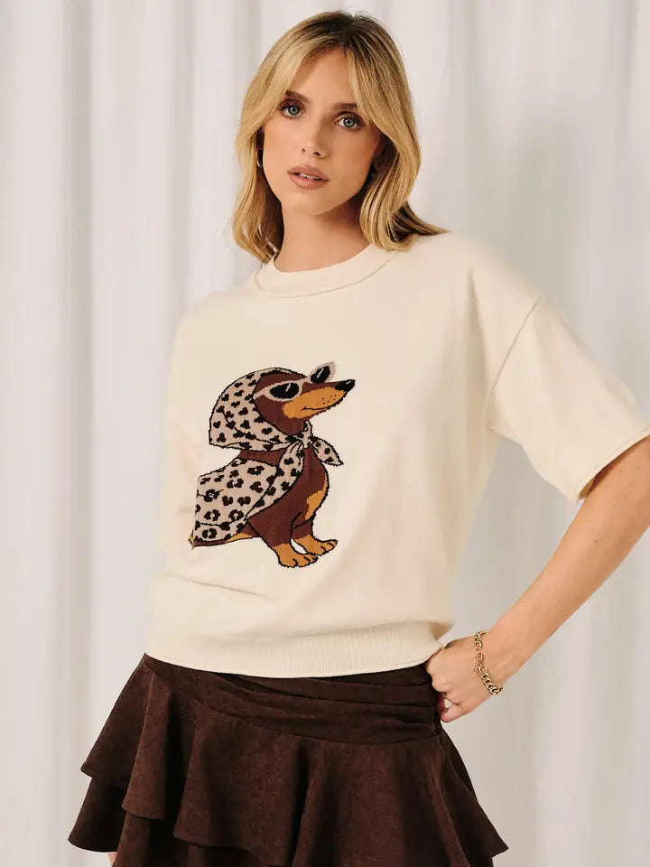 Ivory short sleeve women's sweater top featuring a dachshund wearing a brown and leopard print scarf and cape with ribbed hem.