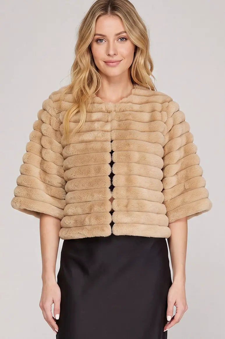 Women's champagne beige cropped faux fur jacket featuring plush horizontal ribbed detailing, a rounded neckline, three-quarter sleeves, and an elegant soft faux fur finish.