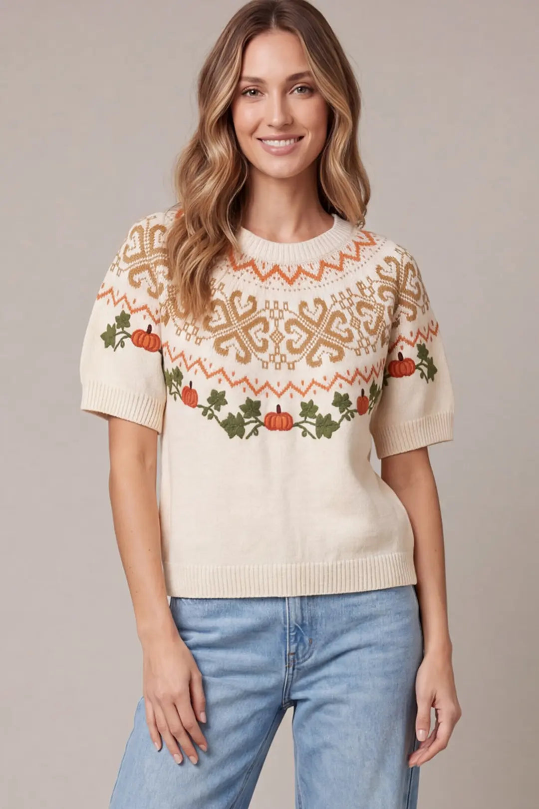 Women's ivory short-sleeve pumpkin Fair Isle sweater featuring embroidered orange pumpkins, green leafy vines, caramel knit patterns, crew neckline, and ribbed trim.