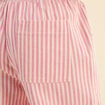 Close-up of a pink and off-white vertically striped fabric garment, showing a side pocket and gathered waistband against a light beige background.
