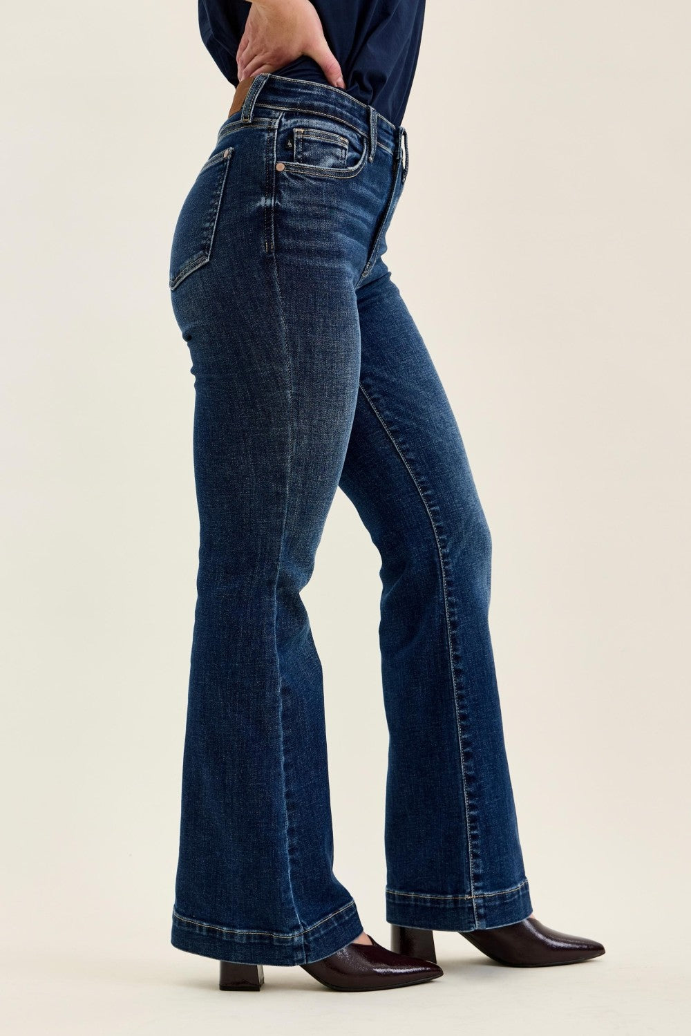 Dark wash Judy Blue petite flare trouser denim with high-rise fit, wide leg, and classic five-pocket design, styled with ankle boots.