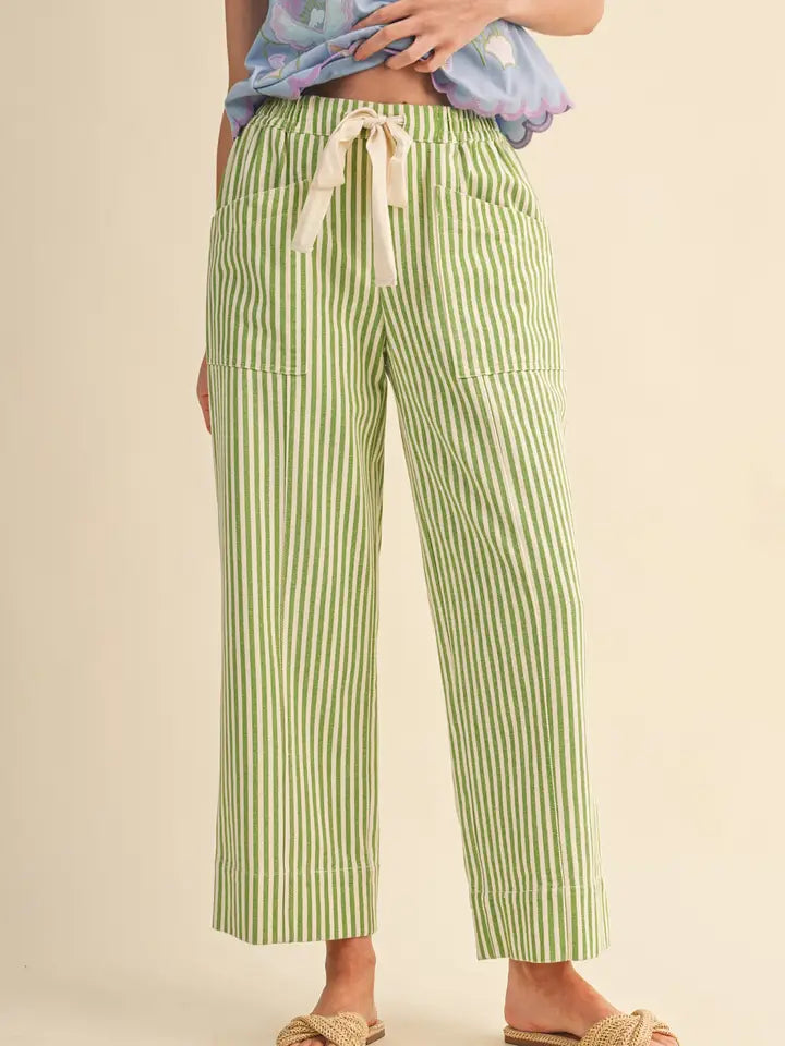Green and white striped pants worn by a person on a beige background