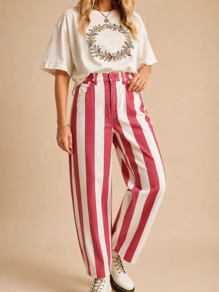 Woman wearing pink and ivory vertical striped high-rise cotton pants by J.NNA styled with an oversized ivory graphic tee and boots.