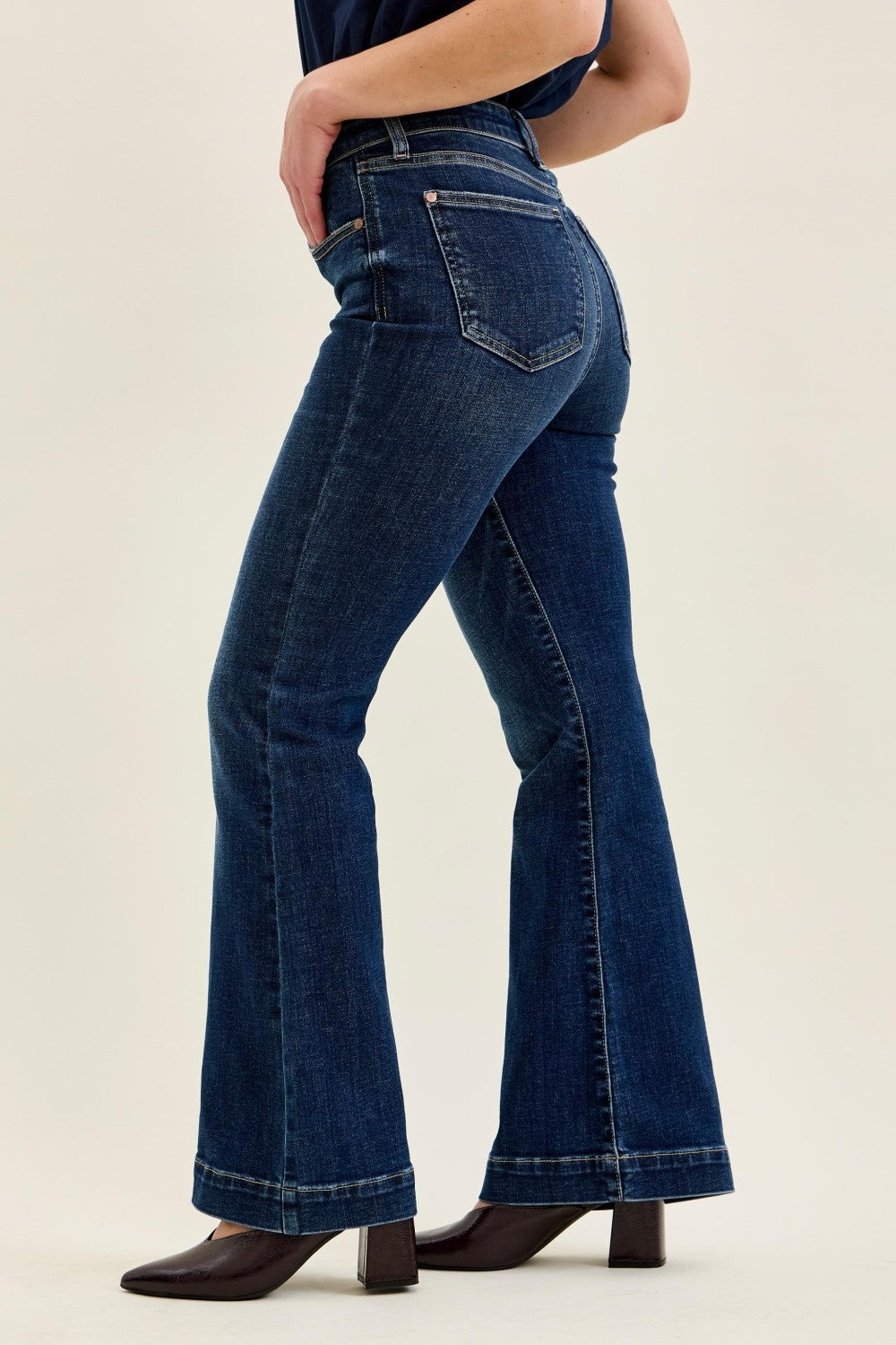 Dark wash Judy Blue petite flare trouser denim with high-rise fit, wide leg, and classic five-pocket design, styled with brown heeled boots.