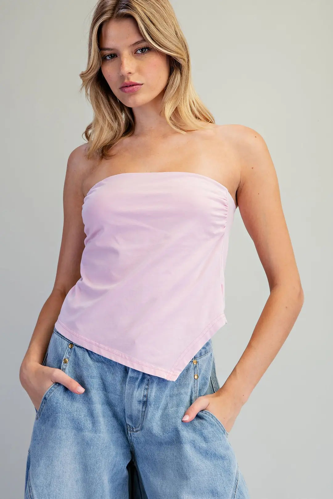 Women's blush pink strapless fitted top with a straight neckline and asymmetrical pointed hem.