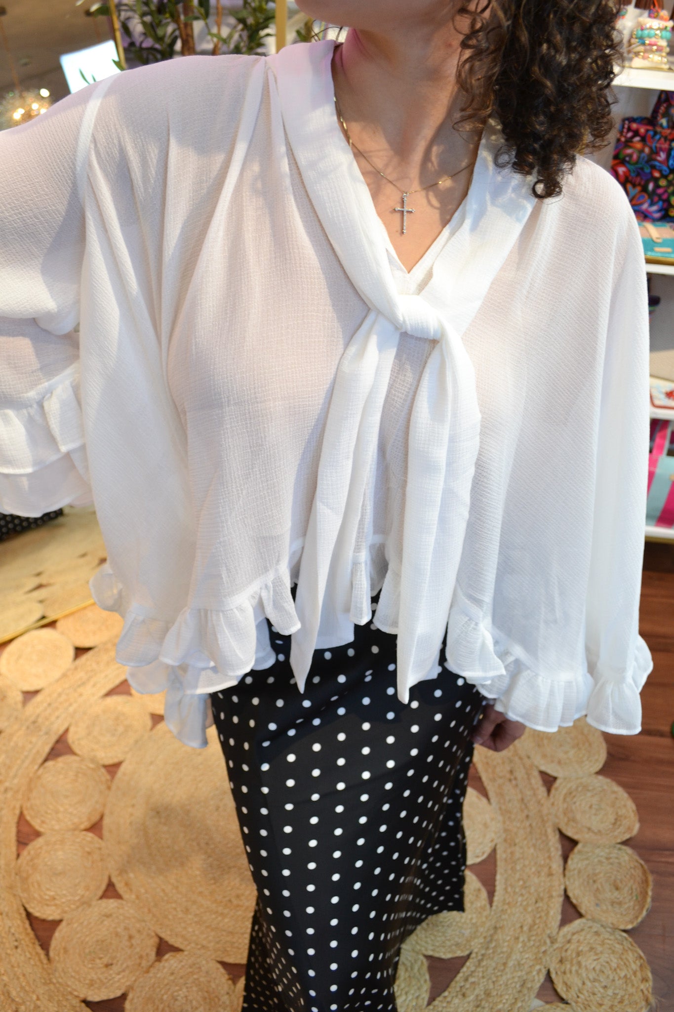 Boutique white long sleeve blouse featuring a tie-neck detail, airy fabric, and layered ruffle cuffs for a romantic look.