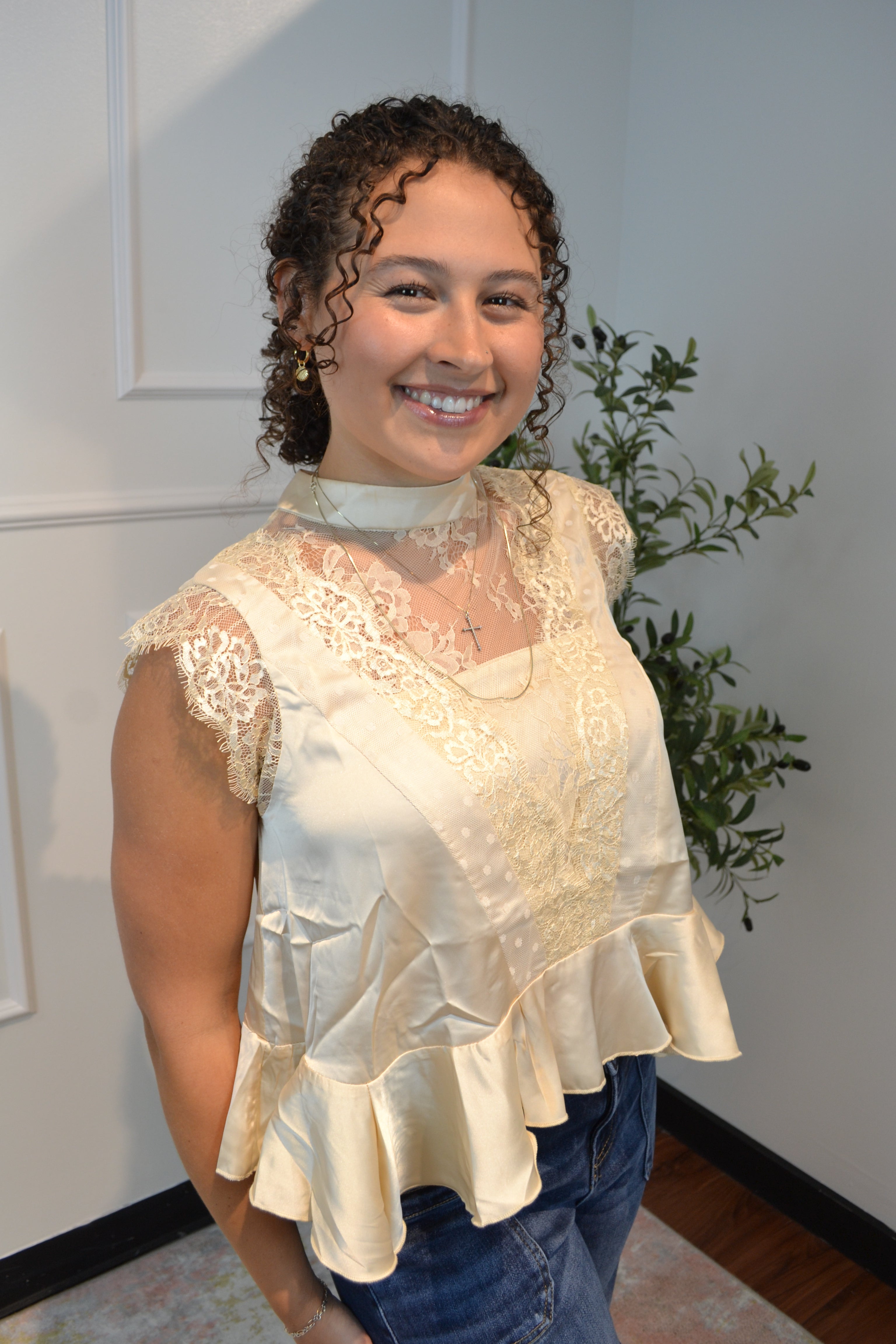 Romantic ivory satin blouse with floral lace accents and ruffle hem.