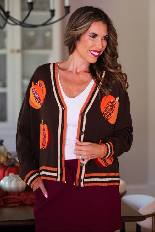 Close-up of woman in a pumpkin patch cardigan featuring orange pumpkin appliqués with sequin and floral details, layered over a white top