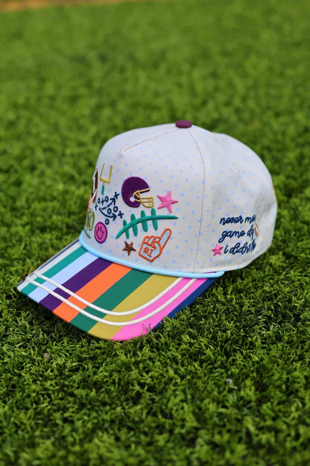 Back view of white baseball cap with multicolored embroidered stars, adjustable strap, and polka dot pattern, ideal for sports fans