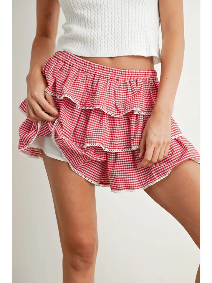 Women’s red and white gingham ruffle skort featuring a tiered design, white trim and elastic waistband.