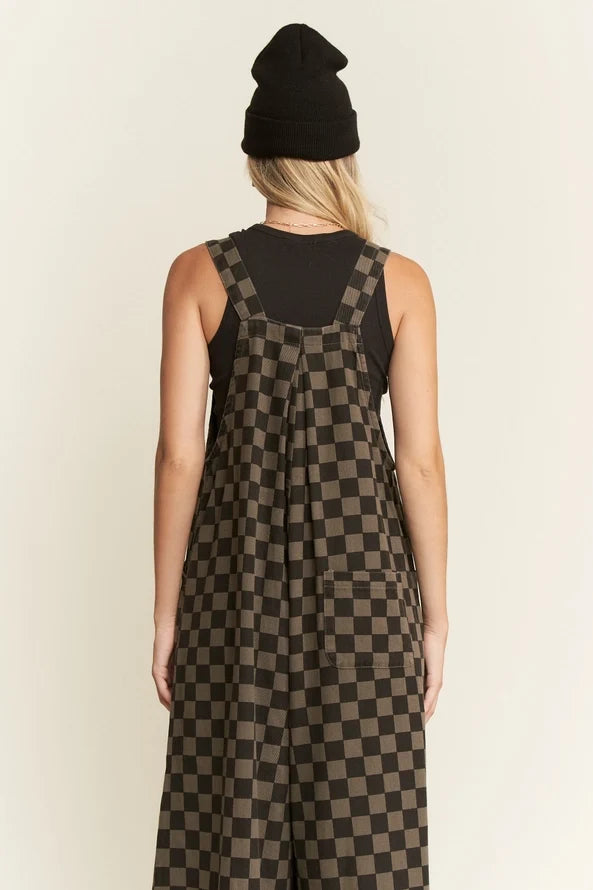 Back view of woman in wide leg checkerboard overalls with black tank top, showing back pocket and checkered pattern.