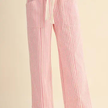 Pink and white vertically striped wide-leg pants with a cream drawstring waist, shown on a model against a solid light beige background.