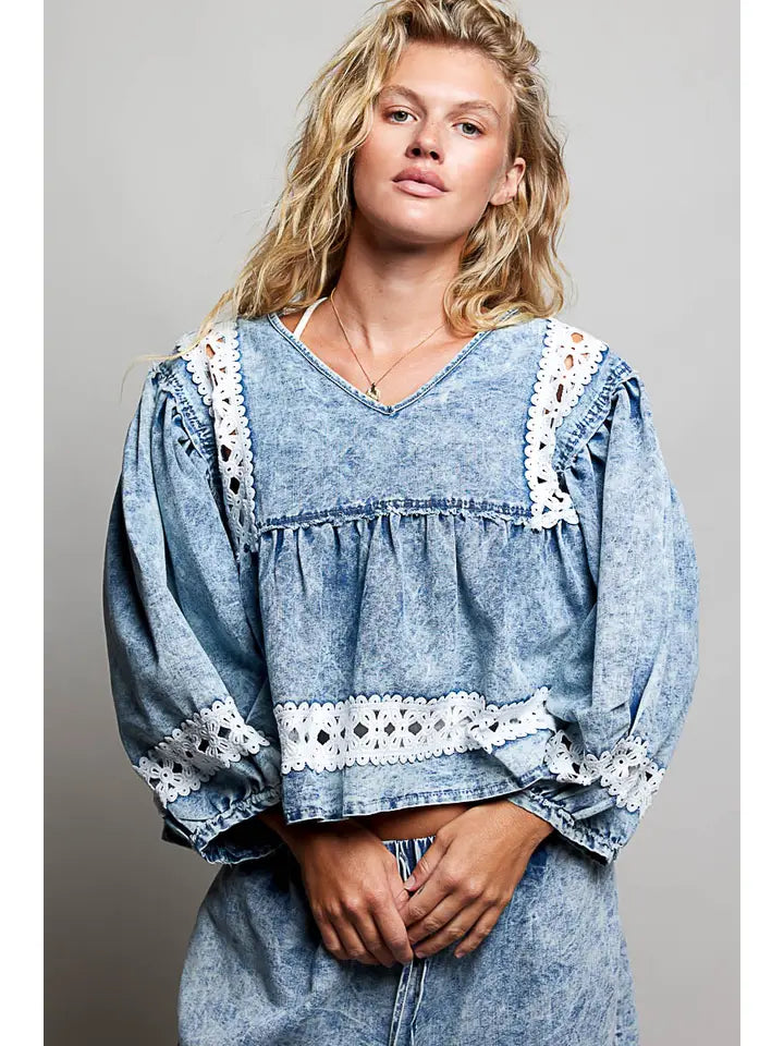 Women's washed blue cotton long sleeve top with V-neckline, gathered bodice and contrasting white crochet lace trim.