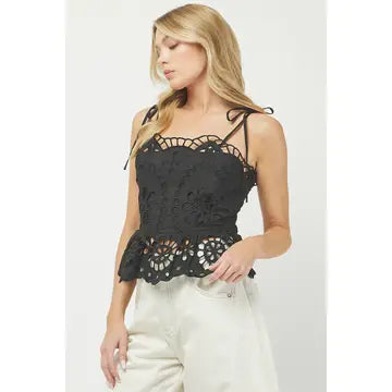 Woman wearing a black lace top and white pants on a white background