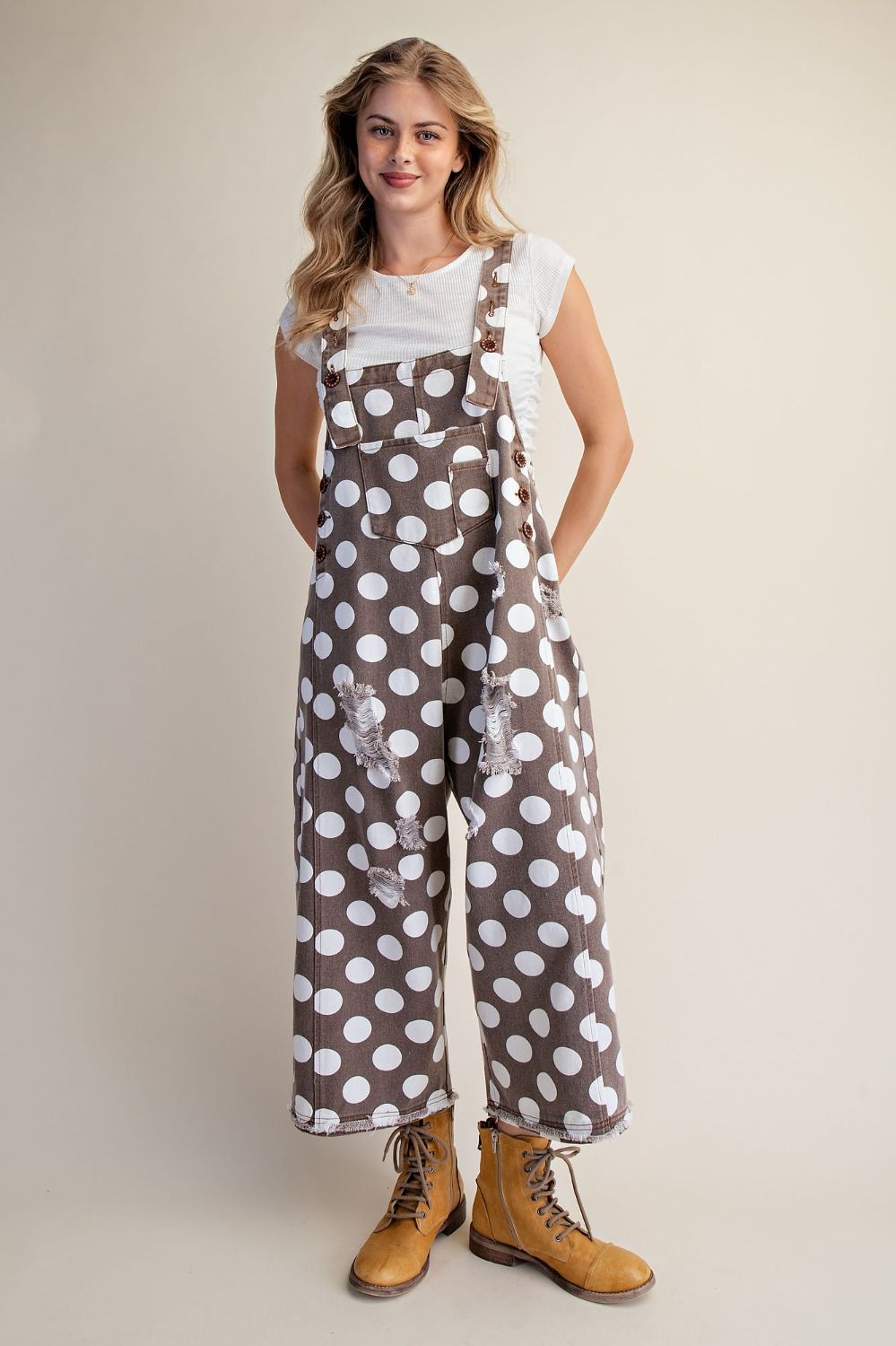 Women’s cocoa brown wide-leg overalls with oversized white polka dots, distressed details, adjustable straps and raw frayed hems.