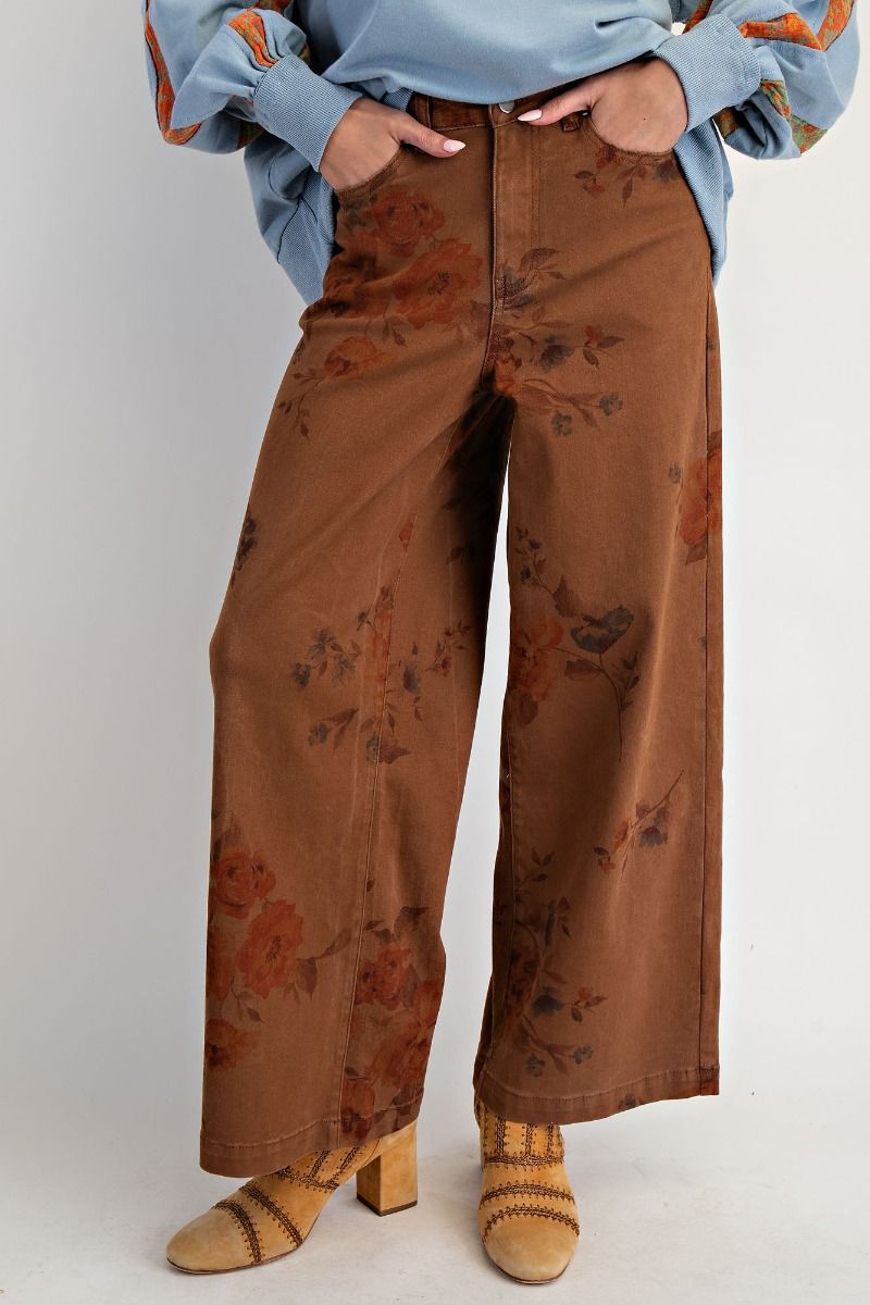 Women’s brown washed wide leg twill pants featuring a vintage faded floral print, five-pocket design, raw hem detail and relaxed silhouette.