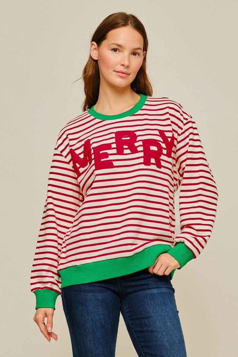 Woman wearing a red and ivory striped Jodifl Christmas sweatshirt with green contrast trim and textured MERRY lettering across the front.