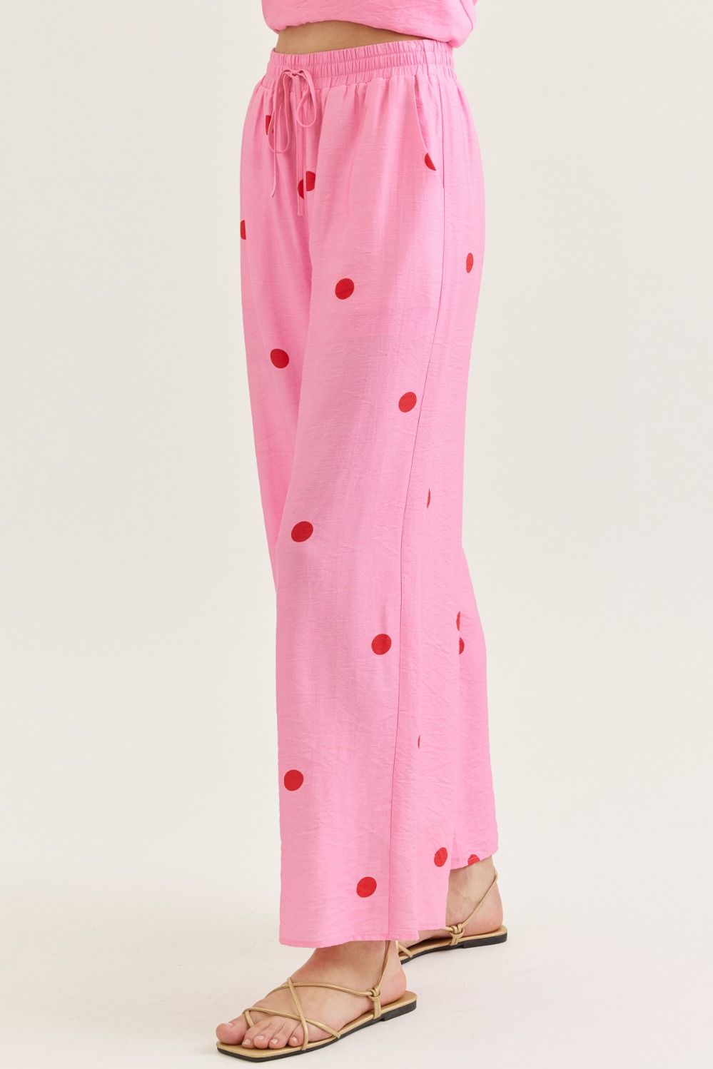 Pink polka dot pants made of lightweight fabric with red dots, elastic waistband with drawstring, wide-leg style, perfect for casual wear - SKU: 12345