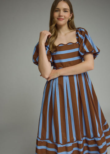 Front view of the brown and blue striped midi dress with puff sleeves, flowy skirt, and side pockets, styled for autumn fashion.