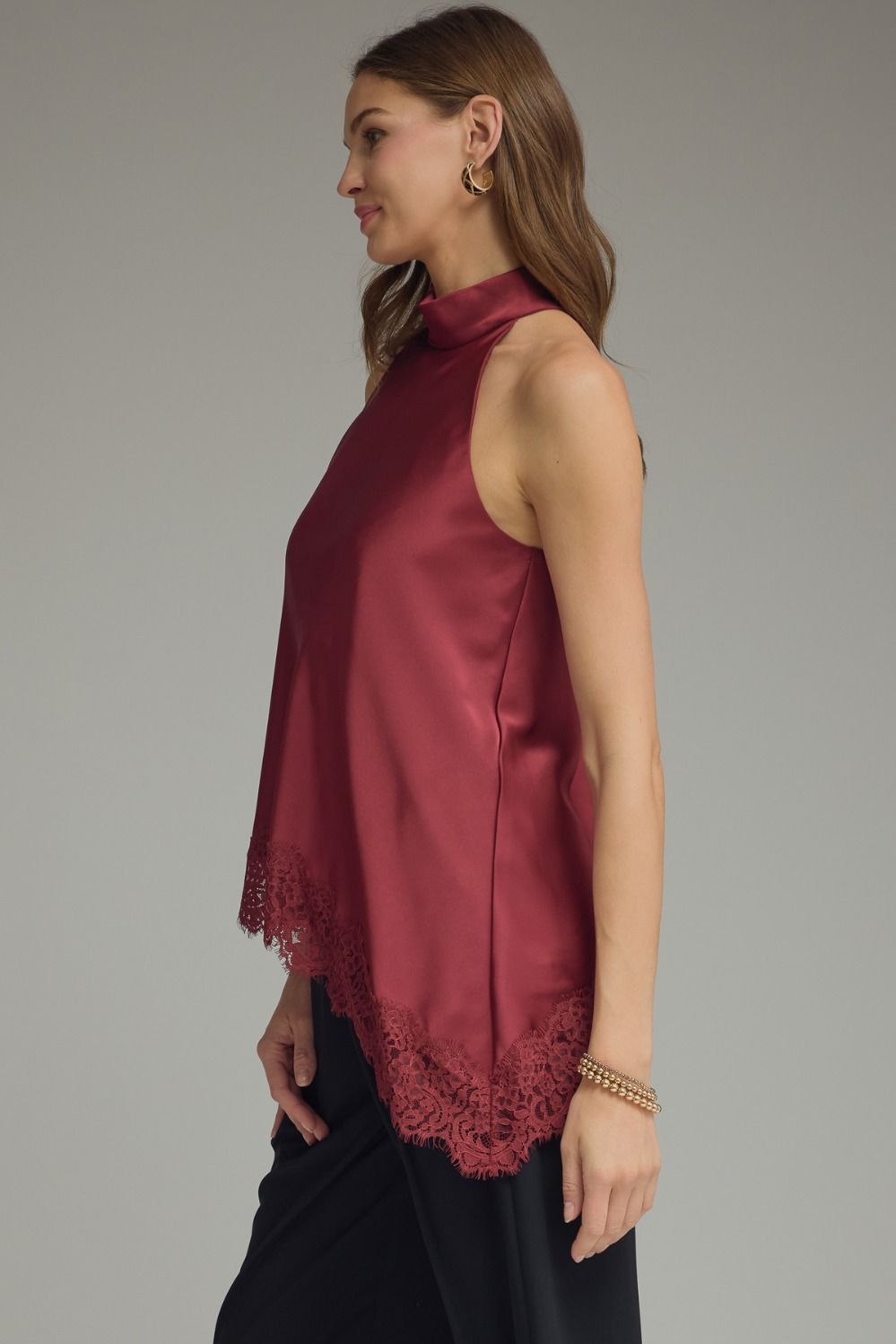 Women’s luxurious satin halter blouse with a mock neckline, lace-trimmed hem, and sleeveless design in black, chocolate brown, and burgundy.