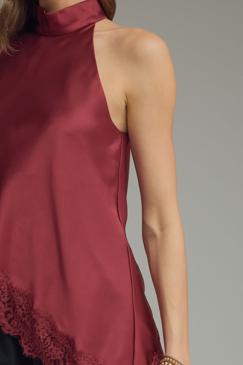 Sophisticated satin sleeveless top for women featuring a high neck, scalloped lace hem, and elegant draped silhouette for day-to-night styling.