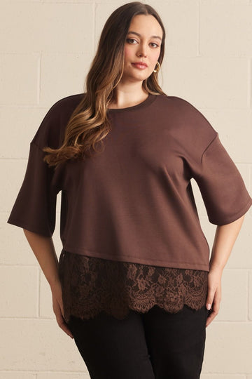 Plus size brown lace asymmetrical tee with relaxed fit, lightweight fabric, scalloped lace hem, worn with black pants, front view