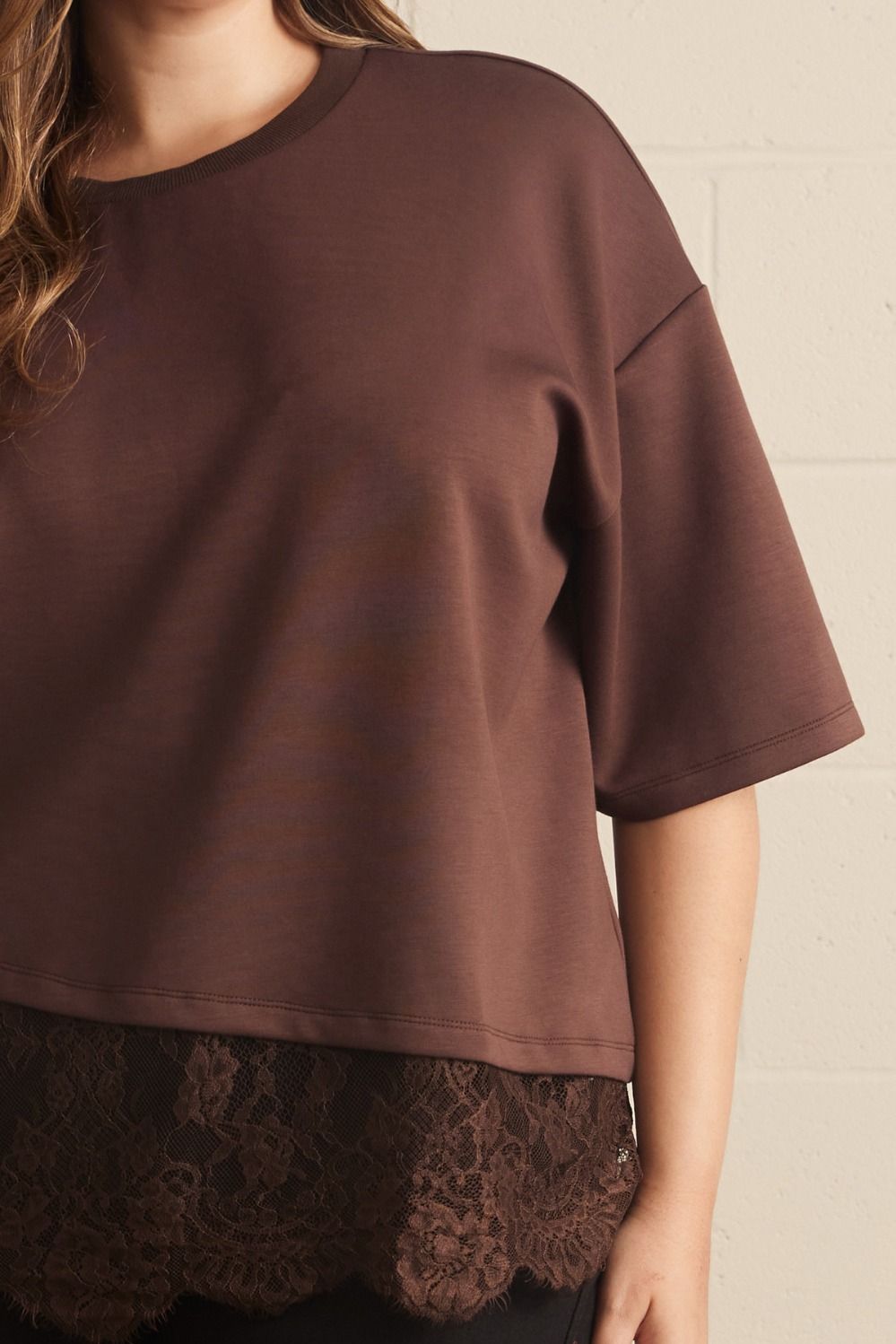 Close-up of brown lace scalloped hem and fabric texture of plus size brown lace asymmetrical tee, showing sleeve detail