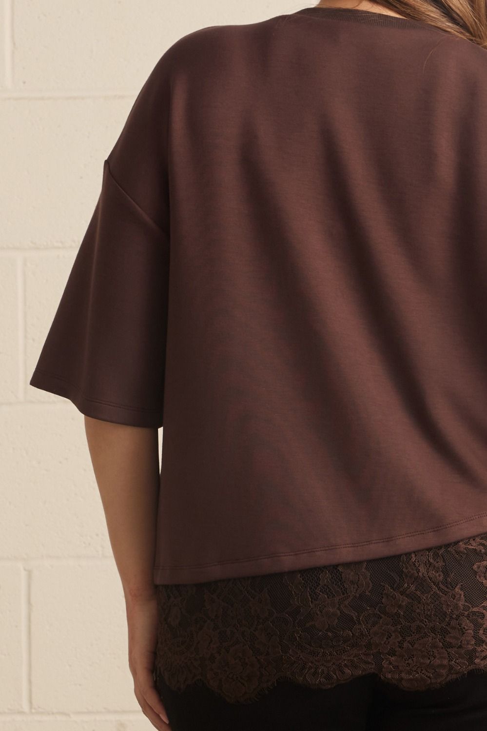 Back view of plus size brown lace asymmetrical tee, showing relaxed fit, short sleeves, and lace hem detail